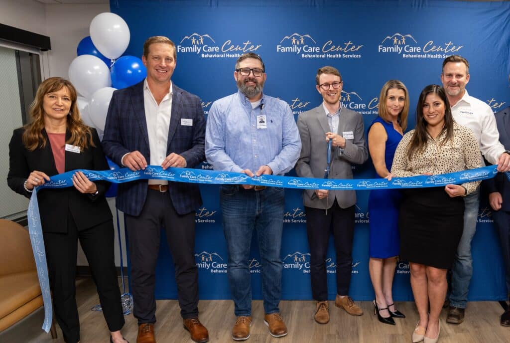 Group of people cutting a ribbon at a clinic opening.