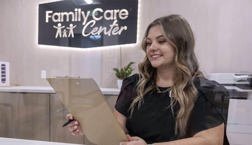 woman at front desk and smiling while looking at a chart